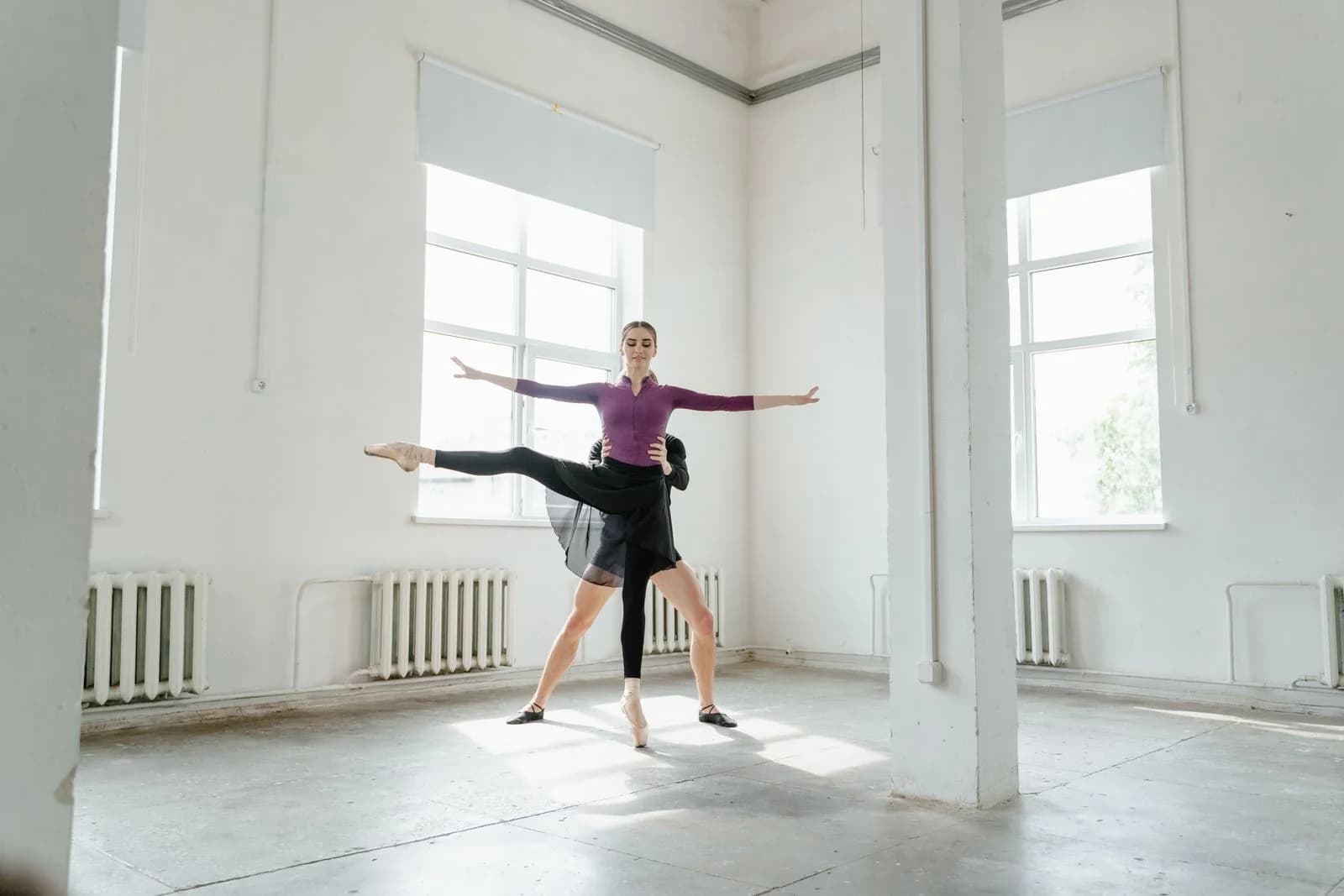 Two ballet dancers practicing in a sunlit studio